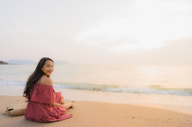 Ocio feliz de la sonrisa de la mujer asiática joven hermosa del retrato en el mar y el océano de la playa