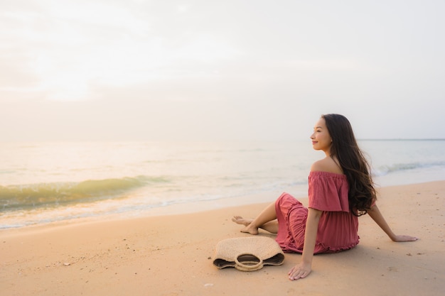 Ocio feliz de la sonrisa de la mujer asiática joven hermosa del retrato en el mar y el océano de la playa