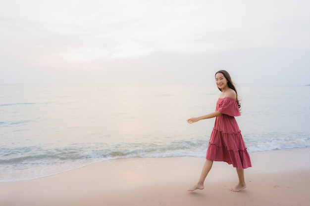 Ocio feliz de la sonrisa de la mujer asiática joven hermosa del retrato en el mar y el océano de la playa