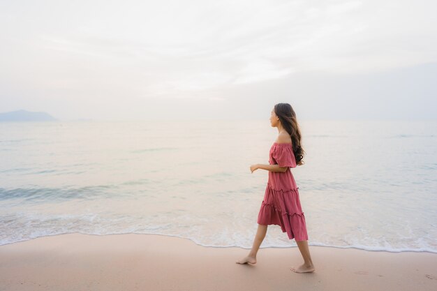 Ocio feliz de la sonrisa de la mujer asiática joven hermosa del retrato en el mar y el océano de la playa