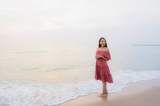 Ocio feliz de la sonrisa de la mujer asiática joven hermosa del retrato en el mar y el océano de la playa