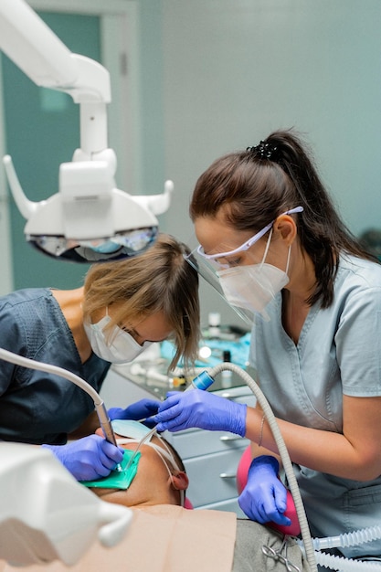Odontología bajo anestesia general. El dentista trata al paciente bajo anestesia general. dentista y asistente en el proceso.
