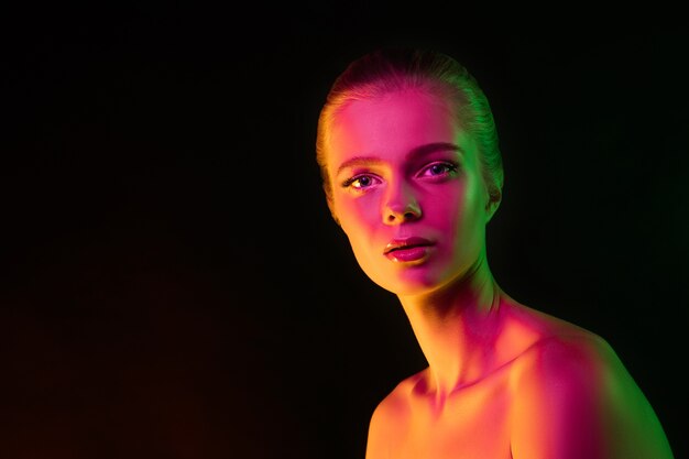 Oferta. Retrato de modelo femenino en luz de neón en la oscuridad. Hermosa mujer caucásica con maquillaje de moda y piel bien cuidada