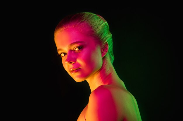 Oferta. Retrato de modelo femenino en luz de neón en la oscuridad. Hermosa mujer caucásica con maquillaje de moda y piel bien cuidada