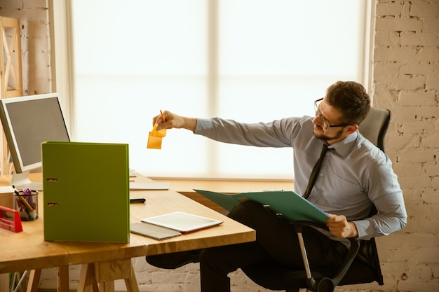 Ofertas. Un joven empresario que trabaja en la oficina, consiguiendo un nuevo lugar de trabajo. Oficinista de sexo masculino joven mientras gestiona después de la promoción. Parece serio, confiado. Negocio, estilo de vida, concepto de nueva vida.