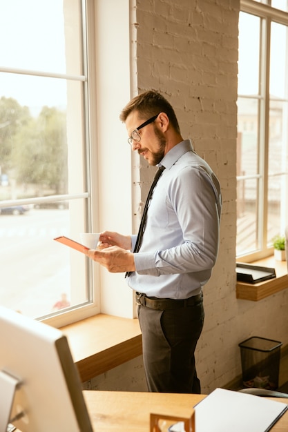 Foto gratuita ofertas. un joven empresario que trabaja en la oficina, consiguiendo un nuevo lugar de trabajo. oficinista de sexo masculino joven mientras gestiona después de la promoción. parece serio, confiado. negocio, estilo de vida, concepto de nueva vida.