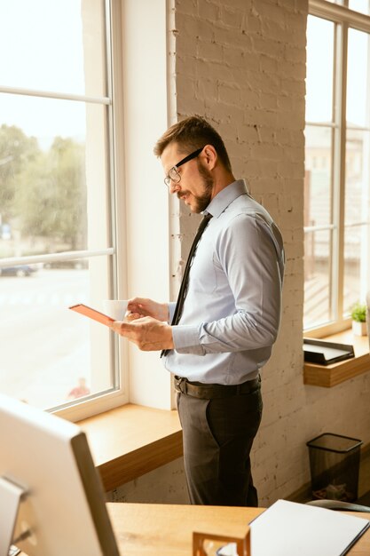 Ofertas. Un joven empresario que trabaja en la oficina, consiguiendo un nuevo lugar de trabajo. Oficinista de sexo masculino joven mientras gestiona después de la promoción. Parece serio, confiado. Negocio, estilo de vida, concepto de nueva vida.