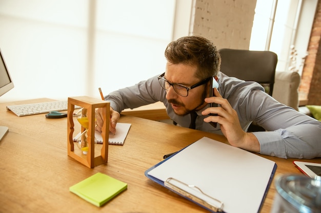 Ofertas. Un joven empresario que trabaja en la oficina, consiguiendo un nuevo lugar de trabajo. Trabajador de oficina masculino joven mientras administra después de la promoción