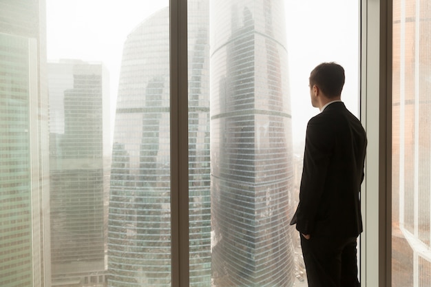 Foto gratuita oficial de la empresa mirando a través de la ventana en la oficina