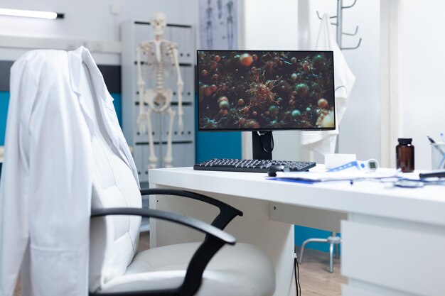 Oficina médica brillante vacía que tiene una computadora en la mesa con una célula de coronavirus en la pantalla durante el examen de virus. Sala de hospital sin nadie equipada con herramientas profesionales. Ilustración de virus