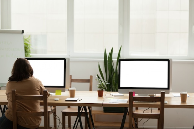 Oficina moderna, espacio de coworking con una mujer que trabaja sola en la computadora.