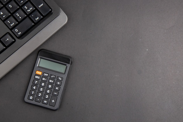 La oficina negra de la vista superior rellena la calculadora del teclado en el espacio de copia de la mesa oscura