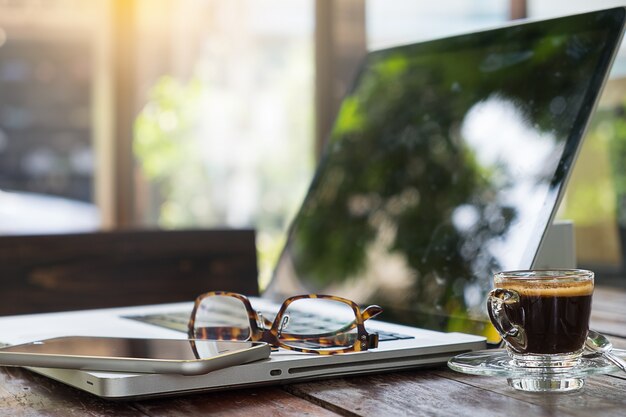 Oficina de trabajo con ordenador portátil y gafas en la mesa de madera