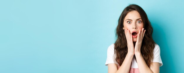 Oh, Dios mío, primer plano retrato de cara de niña sorprendida tocando la cabeza y mirando a la cámara sobresaltada escuchar