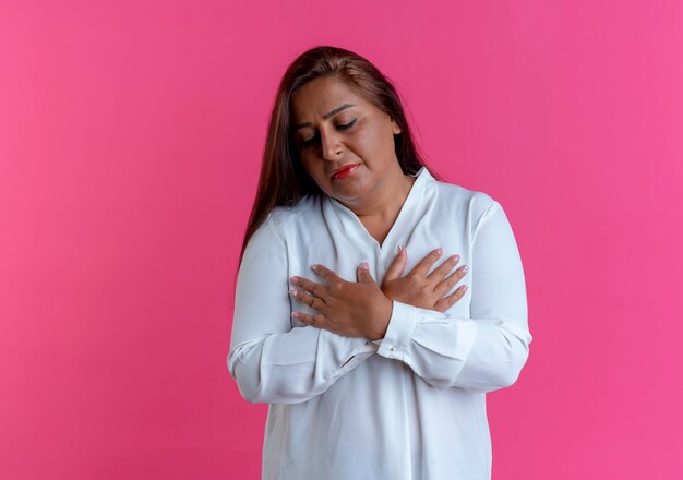 Con los ojos cerrados casual mujer de mediana edad caucásica cruzando las manos aisladas en la pared rosa