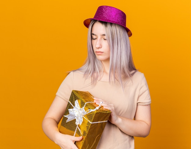 Con los ojos cerrados hermosa joven vistiendo gorro de fiesta con caja de regalo