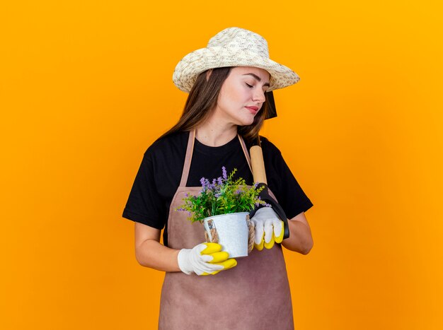 Con los ojos cerrados hermosa niña jardinero con uniforme y sombrero de jardinería