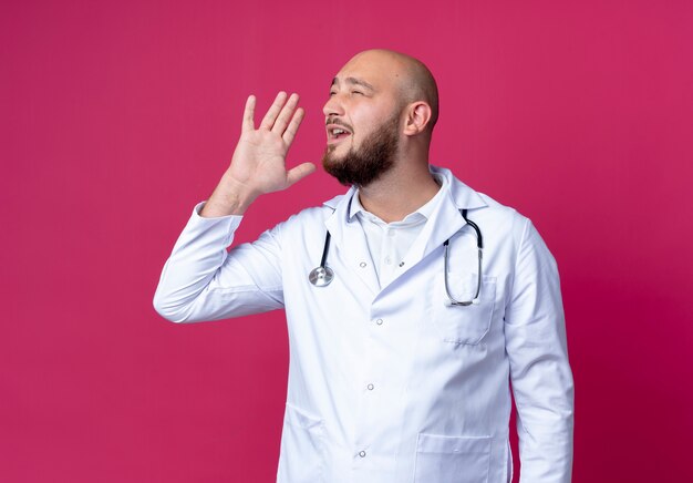 Con los ojos cerrados joven médico vistiendo bata médica y estetoscopio