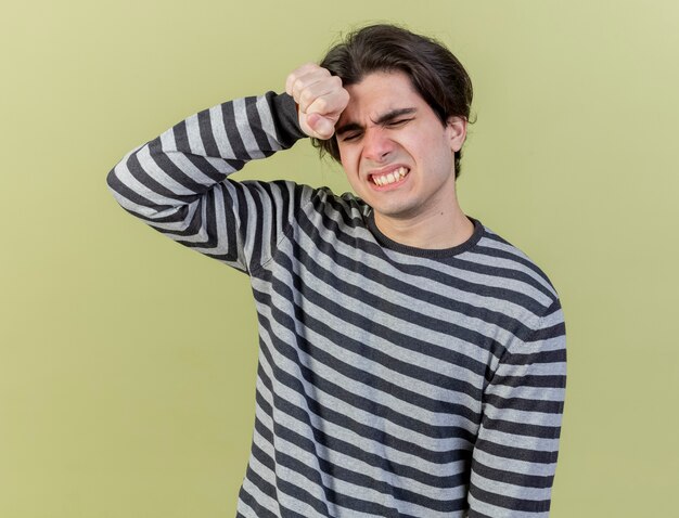 Con los ojos cerrados lamentó el joven enfermo poniendo la mano en la frente aislado sobre fondo verde oliva