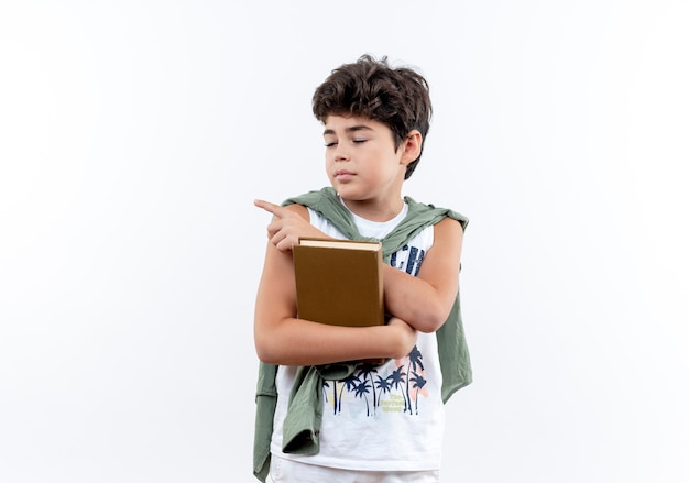 con los ojos cerrados, pequeño colegial sosteniendo un libro y puntos al lado