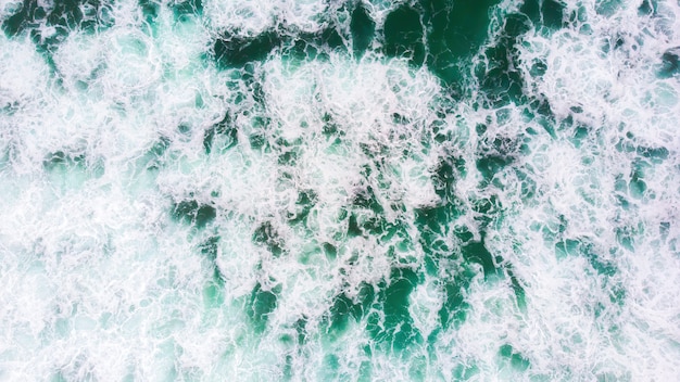 Olas de espuma verde en North Beach en Nazaré, Portugal