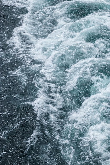 Olas espumosas en la superficie del agua detrás del crucero.