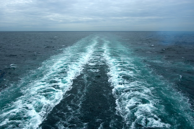 Olas espumosas en la superficie del agua detrás del crucero.