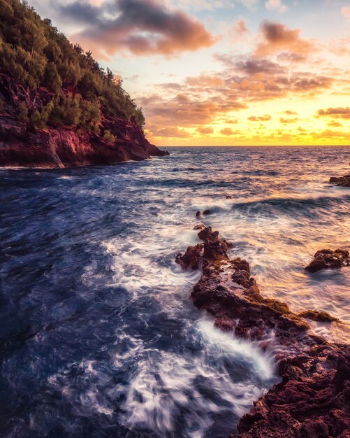 Olas oceánicas rompiendo en las rocas durante el atardecer