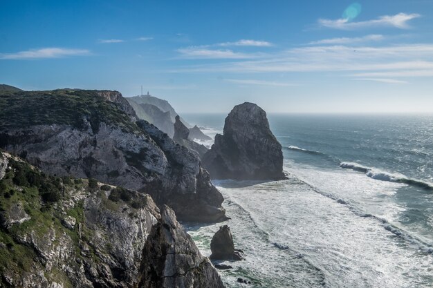 Olas del océano chocando contra la costa rocosa bajo el cielo azul