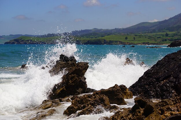 Olas rompiendo sobre rocas con un océano azul detrás de ellas