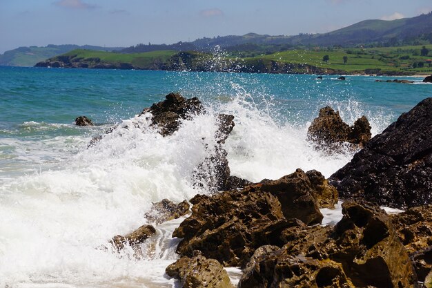 Olas rompiendo sobre rocas con un océano azul detrás de ellas