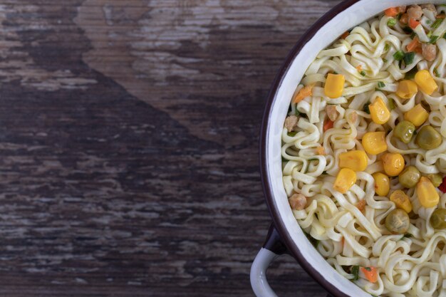 Una olla grande de sabrosos fideos con verduras sobre fondo de mármol