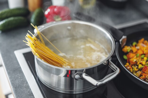 Olla hirviendo con cocinar pasta de espaguetis en la cocina. De cerca