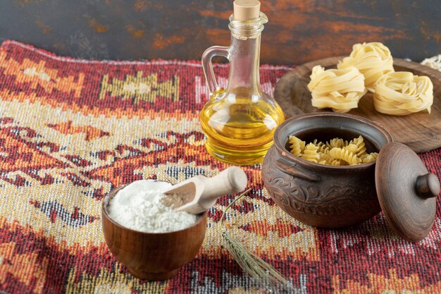 Una olla de macarrones crudos en espiral con pasta enrollada cruda sobre plancha de madera