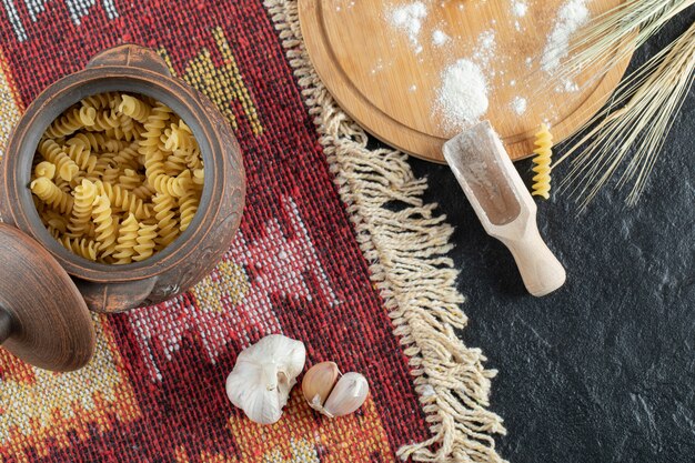 Una olla pequeña de macarrones en espiral sin preparar con ajo y harina.