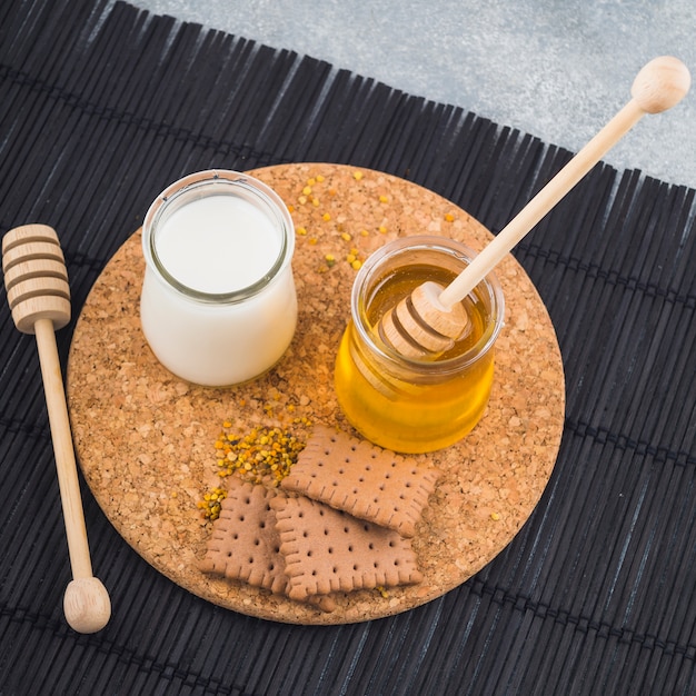 Foto gratuita ollas de leche y miel con galletas y polen de abeja en montaña de corcho