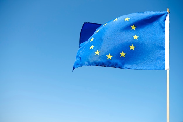 Ondeando la bandera de la Unión Europea sobre el fondo azul.