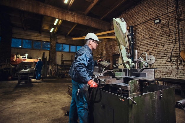 El operador de la fábrica de metal está controlando la máquina herramienta para cortar acero.