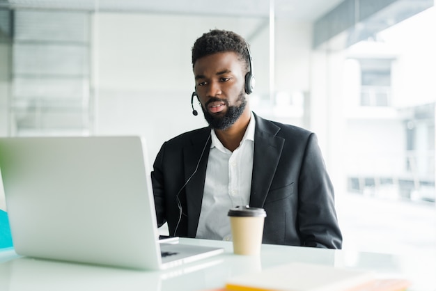 Operador de línea caliente. Retrato de alegre representante de servicio al cliente africano con auriculares en call center