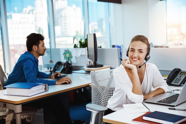 Operador de teléfono de soporte femenino hermoso joven hablando, consultoría, sobre oficina