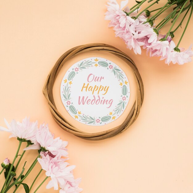 Opinión de alto ángulo del bastidor circular con nuestro texto feliz de la boda y flores rosadas en fondo en colores pastel