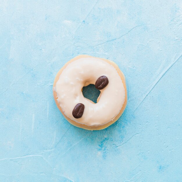 Opinión de alto ángulo de los buñuelos adornados con los granos de café en fondo azul