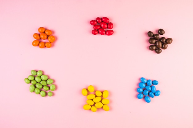 Foto gratuita opinión de alto ángulo de varios caramelos coloridos en fondo rosado