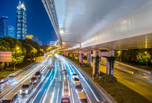 Opinión de la ciudad por la noche con la luz del tráfico y del rastro.