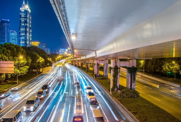 Opinión de la ciudad por la noche con la luz del tráfico y del rastro.