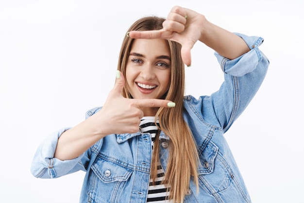 Foto gratuita oportunidades creatividad y concepto de estilo de vida feliz mujer rubia sonriente tratando de capturar el momento hacer marco con las manos y mirar a través de él creando imágenes buscando ángulo recto