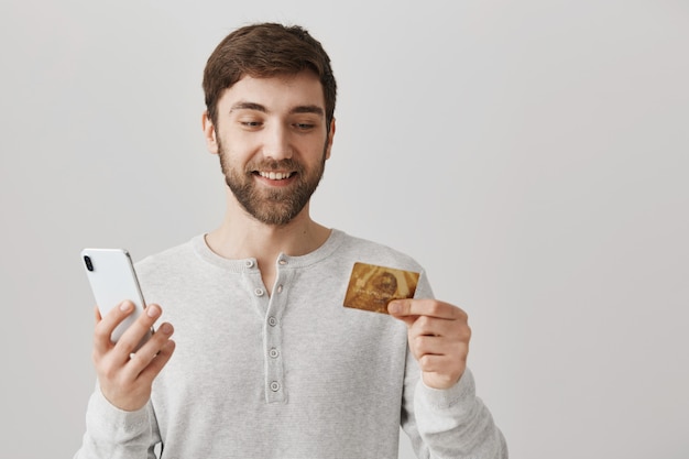 Orden de joven en línea con tarjeta de crédito, mediante teléfono móvil