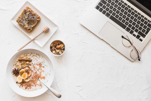 Ordenador portátil y desayuno saludable en el contexto blanco áspero