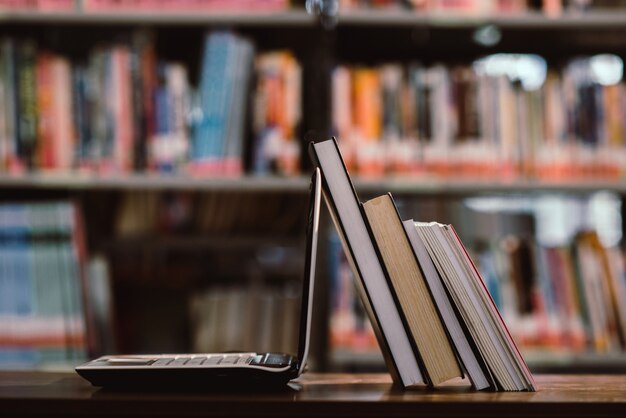 Ordenador portátil y libro de trabajo en la sala de biblioteca