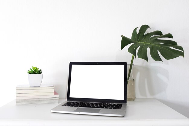 Ordenador portátil con pantalla blanca en blanco en el escritorio de oficina